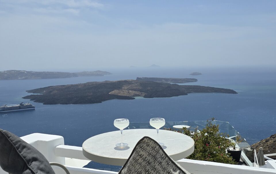 Sunset sea view from On the Rocks Santorini hotel terrace with white lounge chairs