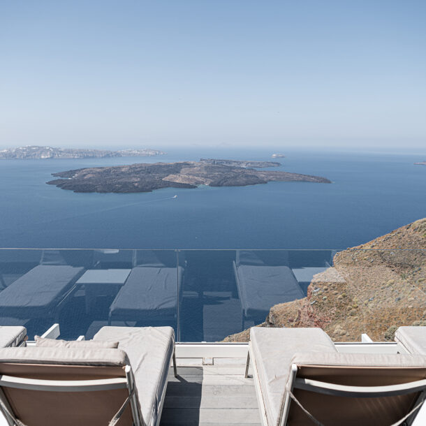 Santorini caldera view from hotel terrace with sunbeds overlooking the volcano and Aegean Sea