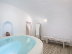 Luxurious Santorini Greece cave pool suite with whitewashed walls, private pool, and minimalist decor.